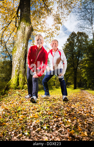 Senior paar tun erstreckt sich auf einem Waldweg im Herbst Stockfoto