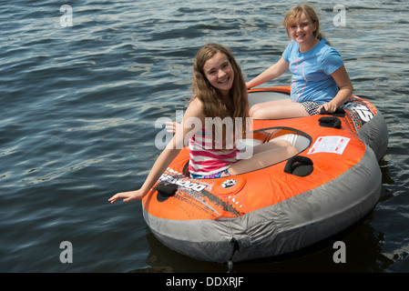 Zwei Mädchen sitzen auf einem Schlauchboot schwimmen in einem See, Lake Of The Woods, Ontario, Kanada Stockfoto