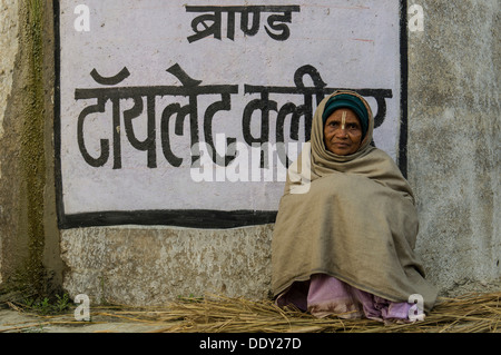 Frau sitzt auf einer Mauer mit Hindi schreiben, während Kumbha Mela Stockfoto