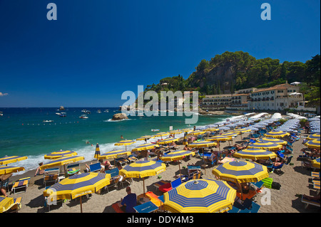 Touristen auf den Strand, Sonnenschirme und Sonne liegen, Bucht von Mazzarò, Taormina, Provinz Messina, Sizilien, Italien Stockfoto