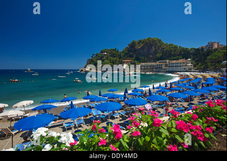 Touristen auf den Strand, Sonnenschirme und Sonne liegen, Bucht von Mazzarò, Taormina, Provinz Messina, Sizilien, Italien Stockfoto