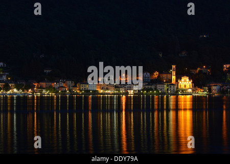 Dorf von Porto Ceresio mit Pfarrei Kirche der Chiesa Sancto Ambrosio am Lago di Lugano oder Lago di Lugano in der Nacht Stockfoto