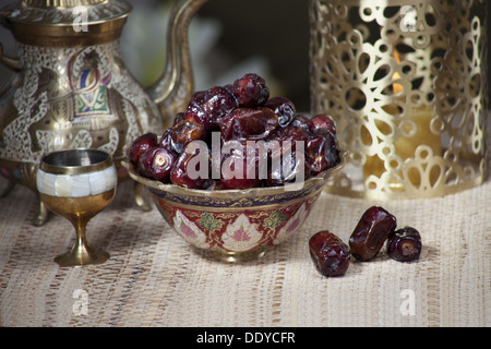 Frische Datteln in dekorative Schale mit Wasserkocher und Cup auf einer Tischdecke Stockfoto