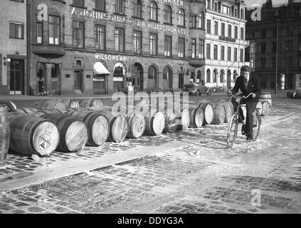 Radfahrer reiten durch evaporierte Milch aus Fässern am Kai verschüttet, Malmö, Schweden, Mai 1947. Artist: Otto Ohm Stockfoto