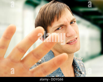 Junger Mann mit einem ernsten Gesicht trägt eine Jeansjacke Nieten, defensive Geste, portrait Stockfoto