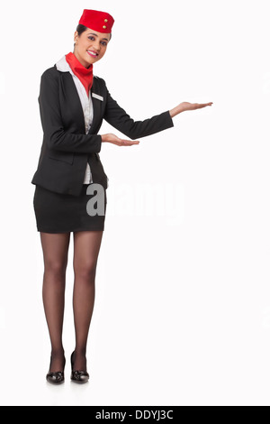 In voller Länge Portrait von einer Stewardess einladend vor weißem Hintergrund Stockfoto