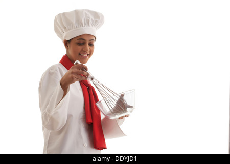 Junge Köchin halten mischenden Schüssel und Draht Schneebesen isoliert auf weißem Hintergrund Stockfoto