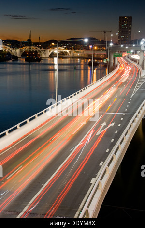Verkehrsströme entlang der Pacific Motorway und Victoria Bridge während der Hauptverkehrszeit in der Abenddämmerung. Stockfoto