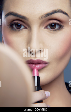 Ernste junge Frau Auftragen von Lippenstift Stockfoto