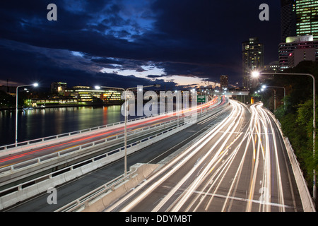Verkehrsströme entlang der Pacific Motorway und Victoria Bridge während der Hauptverkehrszeit in der Abenddämmerung. Stockfoto