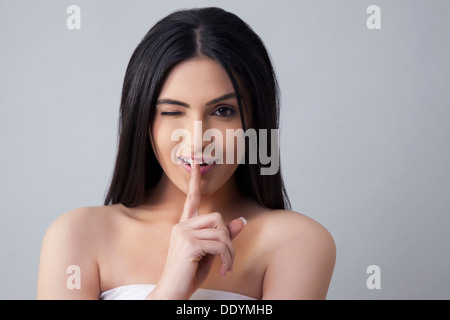 Schöne zwinkernde Frau Gesten für Stille über farbigen Hintergrund Stockfoto