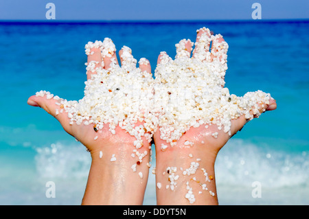Kleinen weißen Steinen in der Hand mit Meer im Hintergrund Stockfoto
