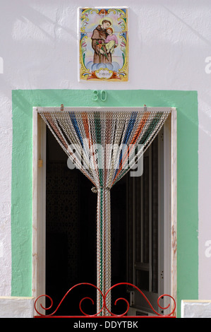 Eine Tür mit Holz Perlen Vorhang aus Bambus mit bemalten Dose - Glasierte keramische Kacheln Azulejos, Baby Jesus in Monte Gordo Algarve, Algarve, die südlichste Region Portugals Stockfoto