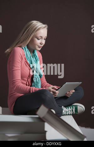 Teenager-Mädchen mit einem Tablet-Computer mit einem Stapel Bücher auf der Vorderseite Stockfoto