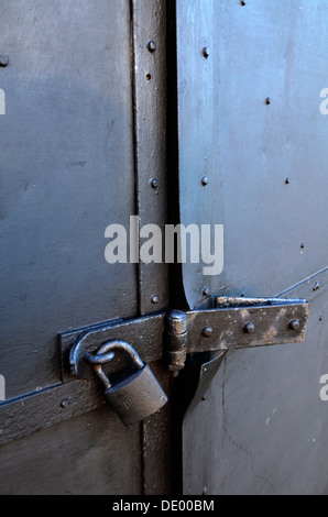 Sicherheit... eine alten Metalltür mit Vorhängeschloss, Hasp und Grundnahrungsmittel gesichert Stockfoto