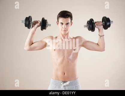 Junger Mann tun Krafttraining mit Hanteln Stockfoto