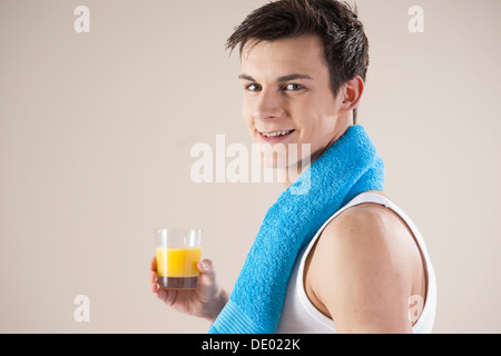 Lächelnder junge Mann nach dem Sport mit einem Glas Saft in der hand Stockfoto