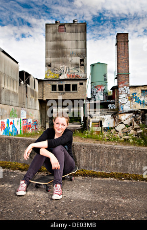 Porträt eines jungen Mädchens sitzen auf einem Skateboard in einem städtischen Gebiet Stockfoto