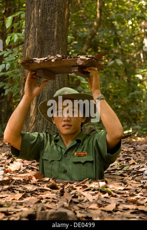 Vietnam-Soldat zeigt den Eingang, dem Tunnelsystem des Vietcong in Chu Chi, Vietnam, Asien Stockfoto