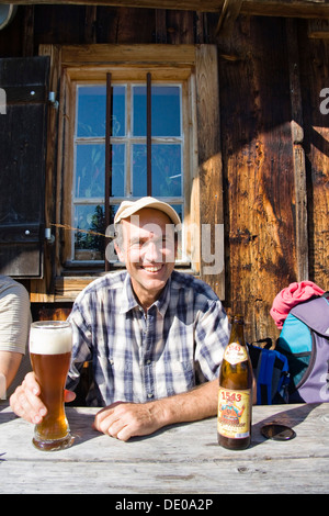 Mann trinken Weizenbier, eine Pause von einer Bergwanderung, Alm, Mitterhuettet Kabine, Alpen Stockfoto