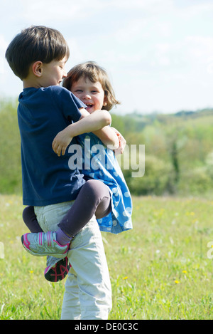 Junge Geschwister umarmen im freien Stockfoto