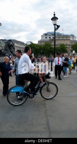 Ein Mann mit dem Boris-Fahrrad in Trafalgar Square mit ein Kind sitzt auf dem Lenker London England UK Stockfoto