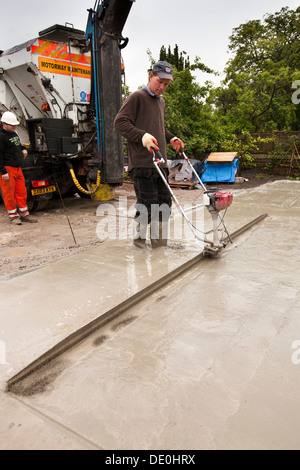 Selbstbau-Haus, Mann mit einstrahliges vibrierende Estrich um zu tamp hinunter Readymixed Betonboden Plattenebene Stockfoto