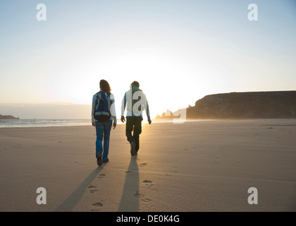 Paar am Strand entlang in Richtung Sonnenuntergang Stockfoto