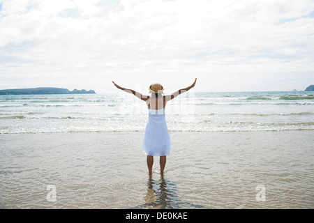 Frau, die Arme ausgestreckt auf einem Strand Stockfoto