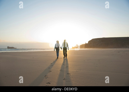 Paar am Strand entlang in Richtung Sonnenuntergang Stockfoto