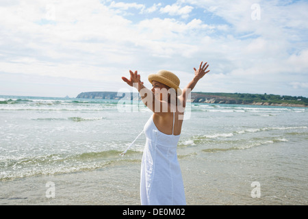 Frau, die Arme ausgestreckt auf einem Strand Stockfoto