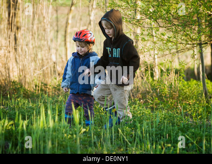 Geschwister, jungen, 8, und Mädchen, 4, zusammen zu spielen, am Ufer eines Teiches Stockfoto