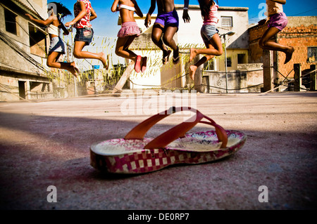 Kinderspiel am Favela Jacarezinho in Rio De Janeiro, Brasilien. 10-14 Jahre-alte glückliche Mädchen Springseil Stockfoto