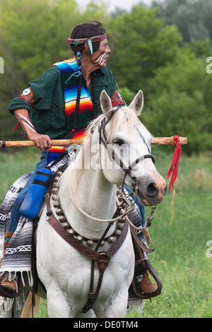 Krieger in Comanche Kleidung, weißes Pferd. Stockfoto