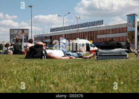 Passagiere warten auf ihren Flügen auf dem Rasen vor dem Berlin-Schönefeld Flughafen-terminal Gebäude Stockfoto