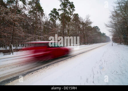 Schneebedeckte Straße im Winter mit einem schnellen Auto vorbei, Mörfelden, Hessen, Deutschland Stockfoto