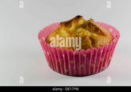 Nahaufnahme von einem köstlichen Backwaren frisch golden Cupcake oder Muffin in eine rosa gepunktete Tasse auf einem neutralen Studio-Hintergrund Stockfoto