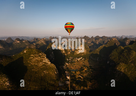 Ein bunter Heißluftballon erhebt sich über dem knorrigen Kalkgipfel in der Provinz Henan in der Nähe von Yangshuo, China Stockfoto