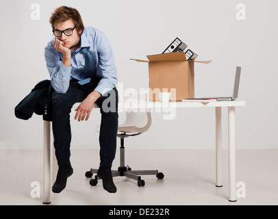 Junger Mann sitzt auf dem Schreibtisch nach gefeuert Stockfoto