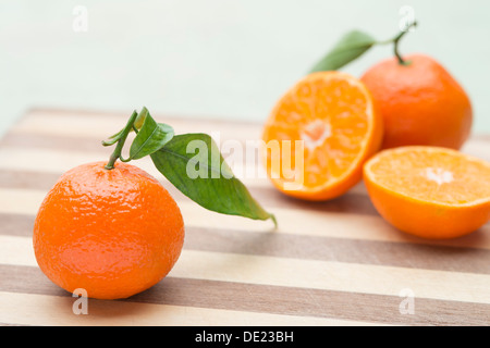 Ein schönes Stillleben Anordnung von Sevilla Orangen mit grünen Blättern auf ein Schneidbrett aus Holz Stockfoto