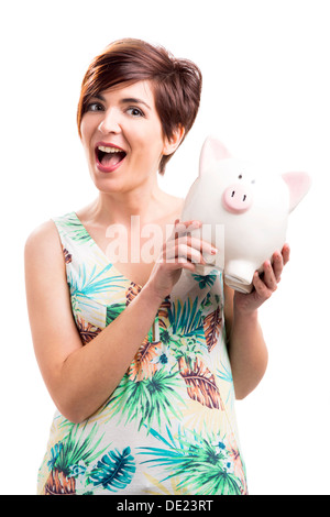 Bewunderte Frau mit einem Sparschwein, isoliert auf einem weißen Hintergrund Stockfoto