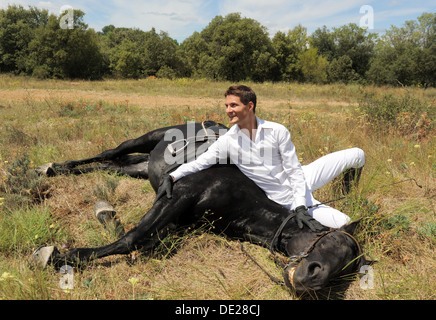 junger Mann und seinem schwarzen Hengst in einem Feld Stockfoto