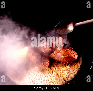 Saftige Steaks Kochen in einer Pfanne mit Butter schaumig, Deutschland Stockfoto