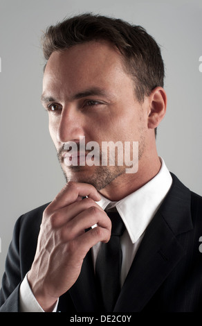 Junge Unternehmer trägt einen Anzug mit der Hand am Kinn, nachdenklich, Porträt Stockfoto