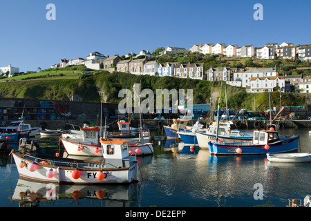 Sonnenlicht beleuchtet blau-weiße Boote vertäut in einem Cornish Fischerdorf in den frühen Morgenstunden. Stockfoto