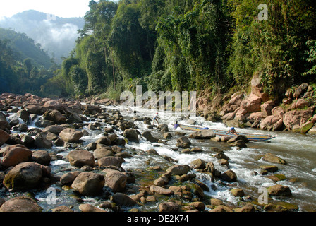 Drei starke junge Männer ziehen und schieben ein Holzboot auf dem Nam Ou Fluss, Wildwasser einspurig Rock und Dschungel an der Küste Ban Stockfoto