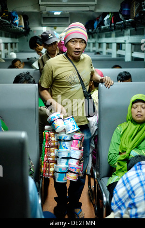 Mann mit Snacks für Passagiere in einem Zug in Java Indonesien Stockfoto