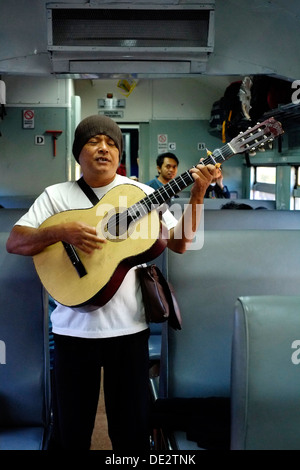 Busker unterhaltsam Passagiere für ein paar Münzen in einem Zug in Java Indonesien Stockfoto