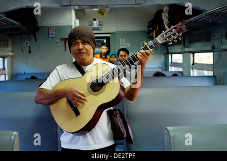 Busker unterhält Passagiere für ein paar Münzen in einem Zug in Java Indonesien Stockfoto