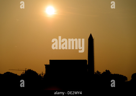 WASHINGTON DC, USA – das Lincoln Memorial und das Washington Monument erscheinen in Silhouette vor der frühen Morgensonne. Gerüste decken einen Teil des Washington Monuments bei Reparaturen zur Behebung von Erdbebenschäden ab. Die markanten Profile der Denkmäler erzeugen einen dramatischen Kontrast im Morgenlicht. Stockfoto